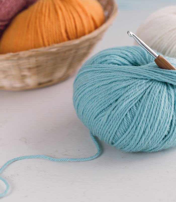 slow crochet making photo of a blue ball of yarn with crochet hook inserted inside 