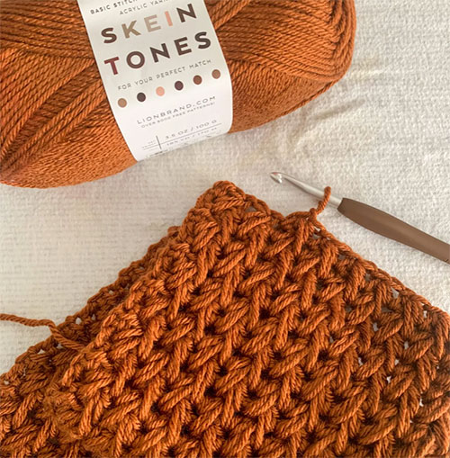 how to crochet the feather stitch photo of a crocheted swatch against a white background showing also the skein of yearn 