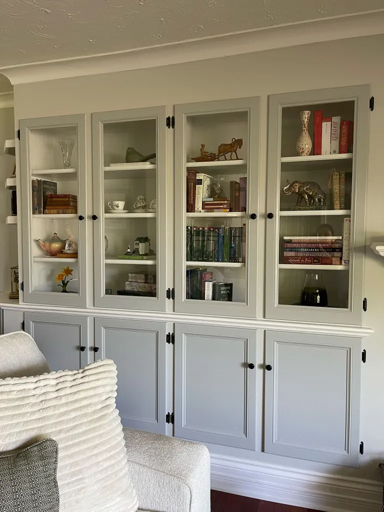 welcoming home photo of a built in book cases with glass doors featuring various decor items and books 