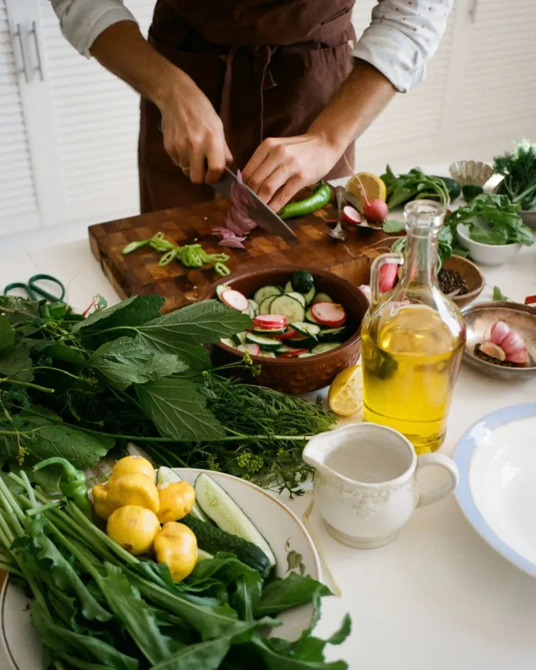 cooking from scratch photo of a man chopping vegetables on a counter with various veggies and herbs 