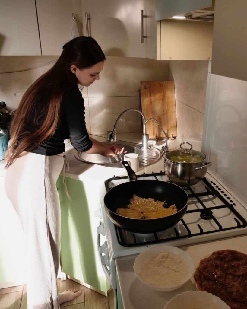 photo of a woman washing dishes next to a stove